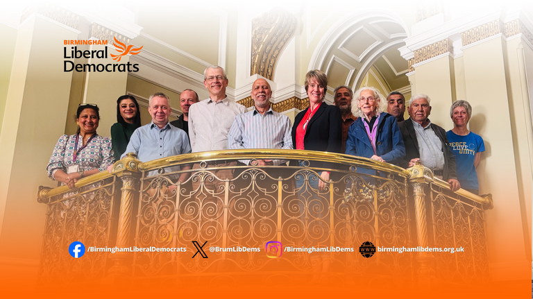 Shot looking up at 12 Lib Dem Councillors standing on a balcony.